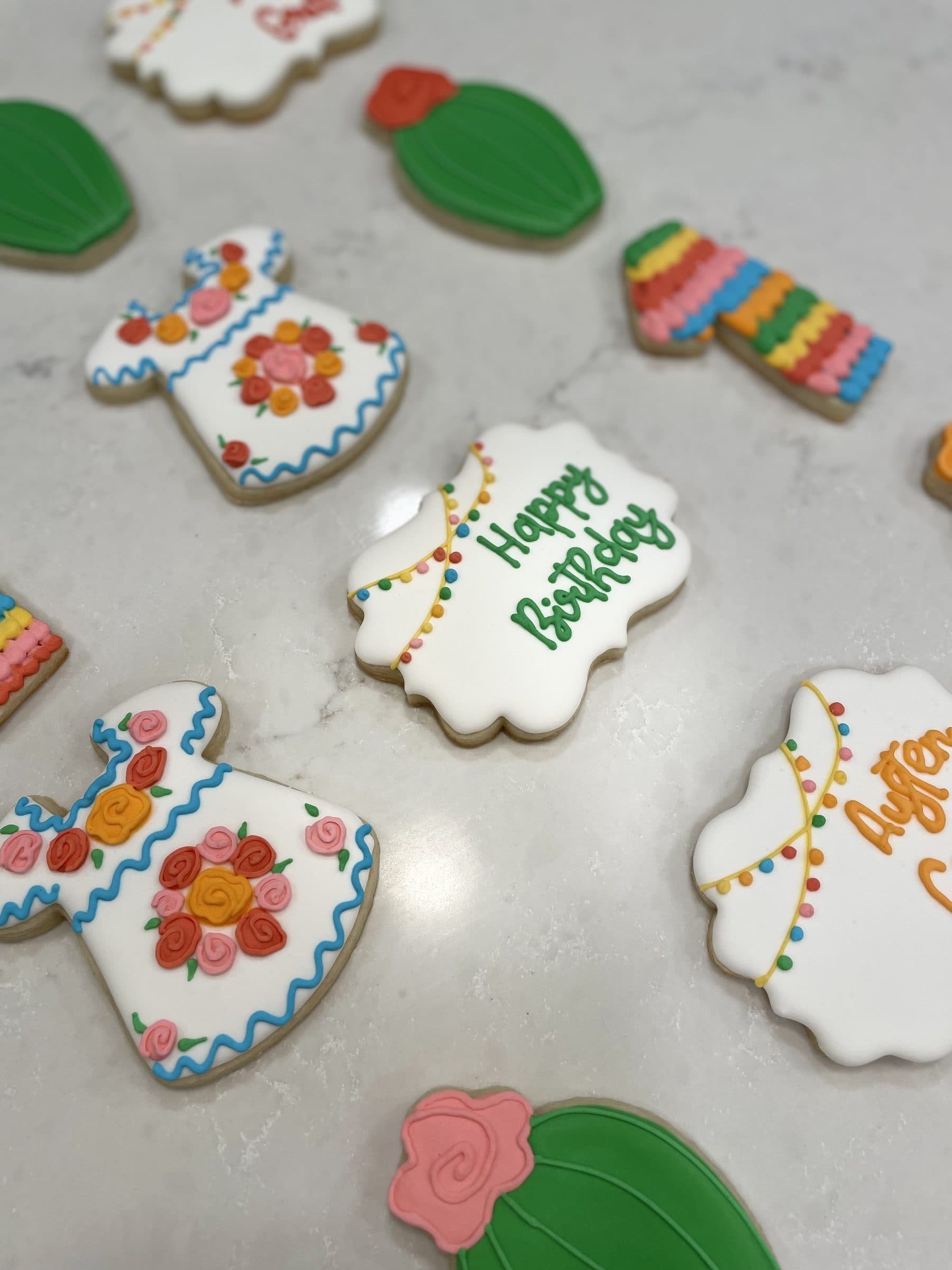 Fiesta birthday cookies with embroidered dresses, cacti, and serapes